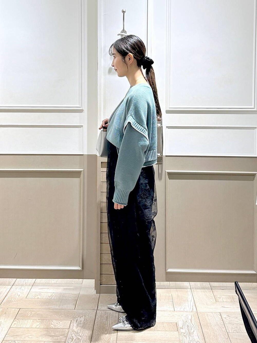 グリーン系のニット/セーター、シルバー系のパンプス、ブラック系のデニムパンツを着用したレディースの秋コーディネートの3枚目の写真