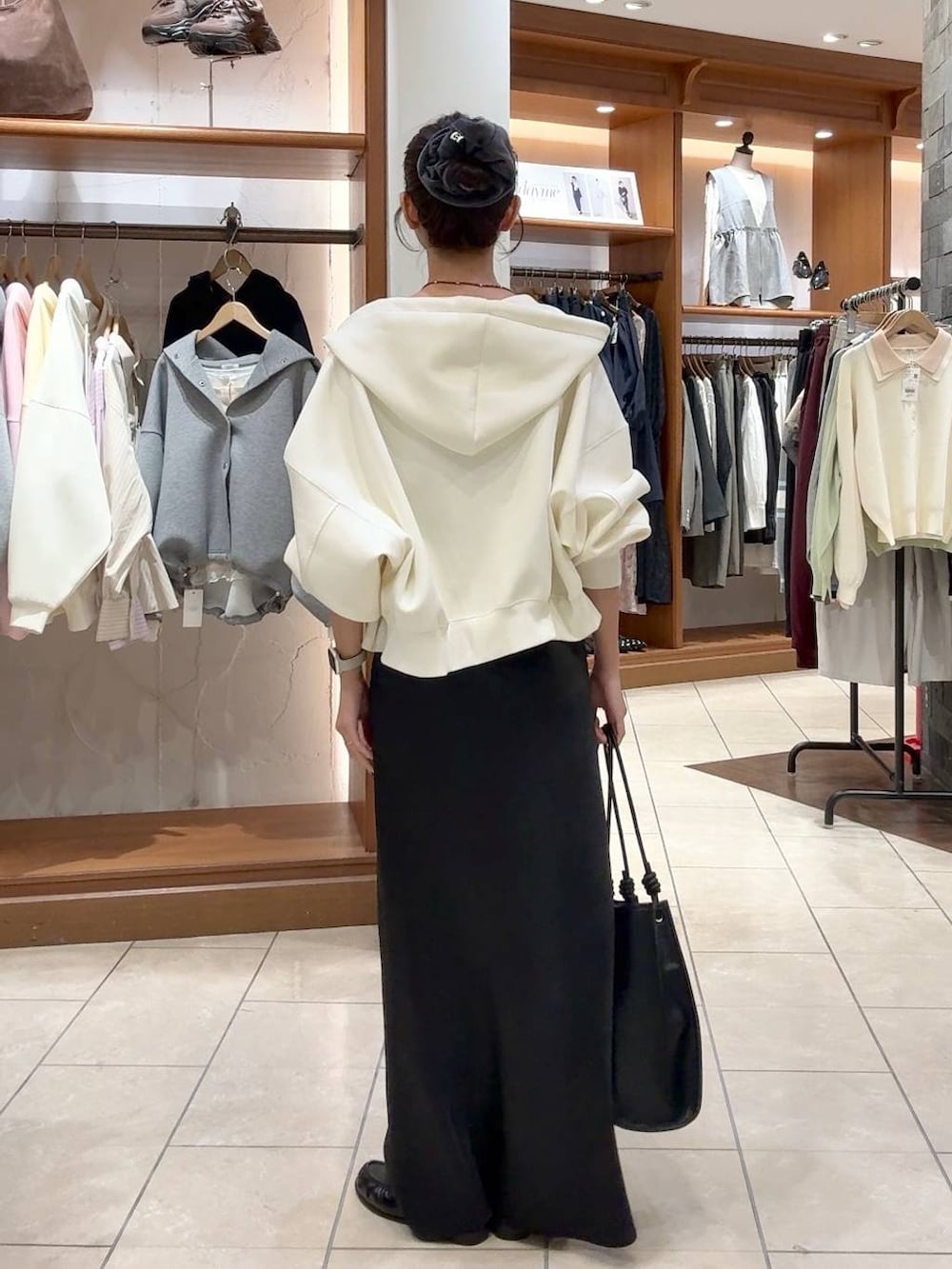 ブラック系のスカート、ベージュ系のパーカー、ブラック系のトートバッグを着用したレディースの春コーディネートの3枚目の写真