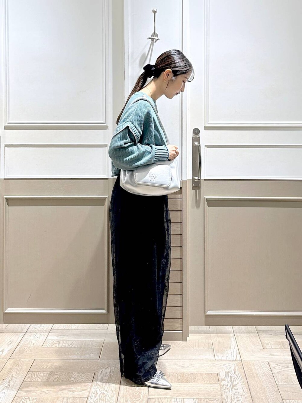 グリーン系のニット/セーター、シルバー系のパンプス、ブラック系のデニムパンツを着用したレディースの秋コーディネートの5枚目の写真