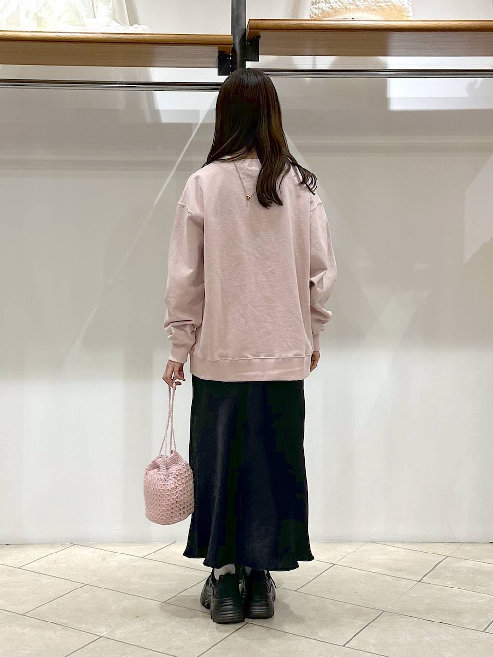 ブラック系のスカート、ブラック系のスニーカー、ピンク系のスウェットを着用したレディースの春コーディネートの3枚目の写真