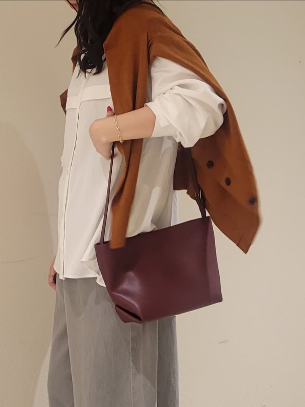 グレー系のデニムパンツ、レッド系のショルダーバッグ、ホワイト系のシャツ/ブラウスを着用したレディースの秋コーディネートの2枚目の写真