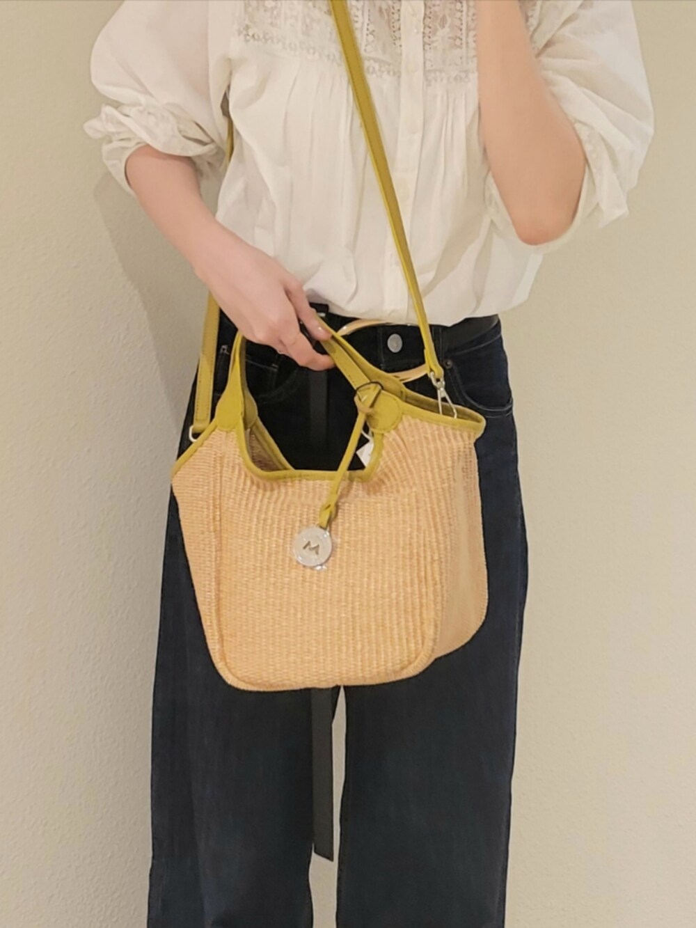 ホワイト系のシャツ/ブラウス、ベージュ系のかごバッグ、ブルー系のデニムパンツを着用したレディースの夏コーディネートの2枚目の写真