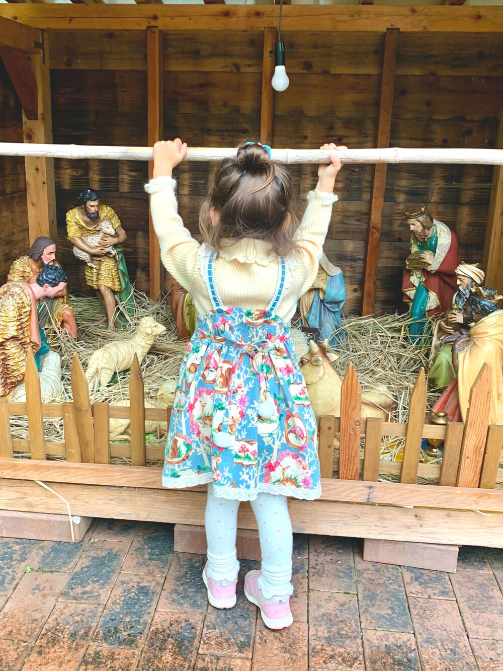 ピンク系のスニーカー、ブルー系のジャンパースカート、ホワイト系のニット/セーターを着用したキッズの冬コーディネートの2枚目の写真