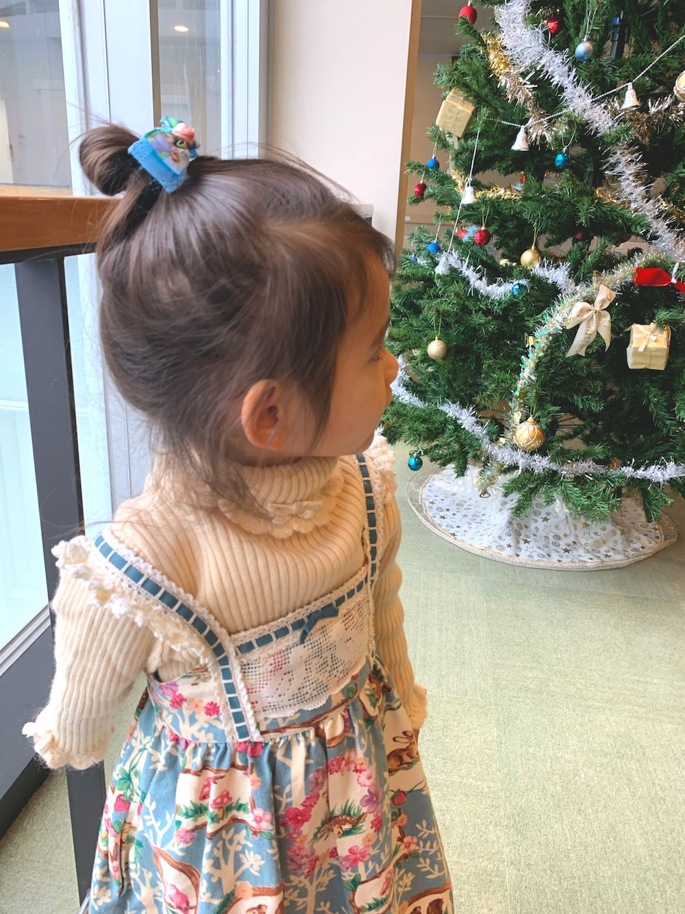 ピンク系のスニーカー、ブルー系のジャンパースカート、ホワイト系のニット/セーターを着用したキッズの冬コーディネートの3枚目の写真