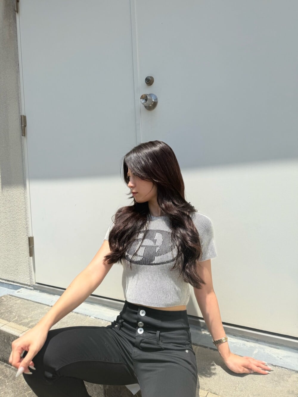 ホワイト系のニット/セーター、ブラック系のデニムパンツ、ブラック系のパンプスを着用したレディースの夏コーディネートの4枚目の写真