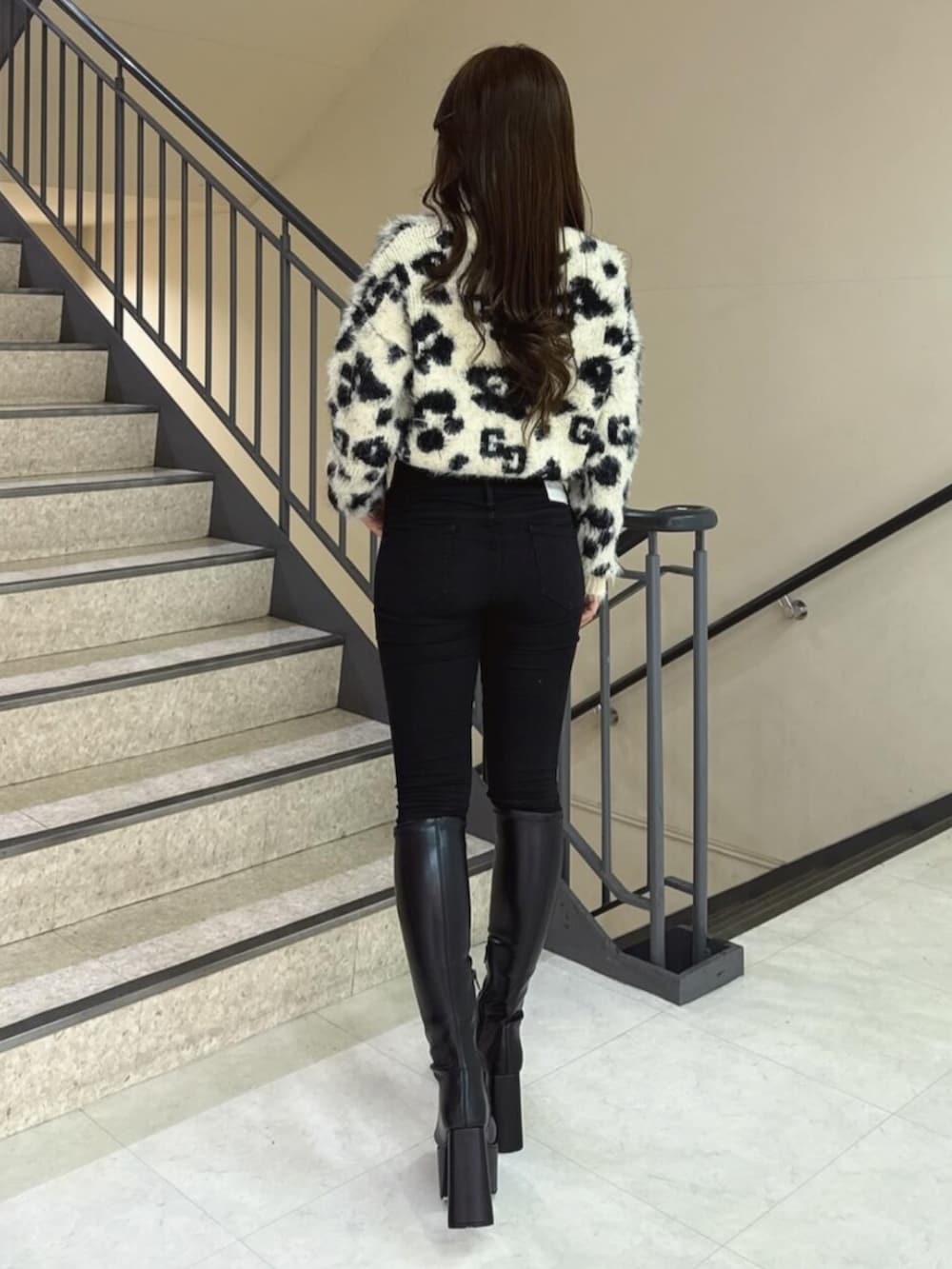 ブラック系のデニムパンツ、ホワイト系のニット/セーター、ブラック系のブーツを着用したレディースの冬コーディネートの3枚目の写真