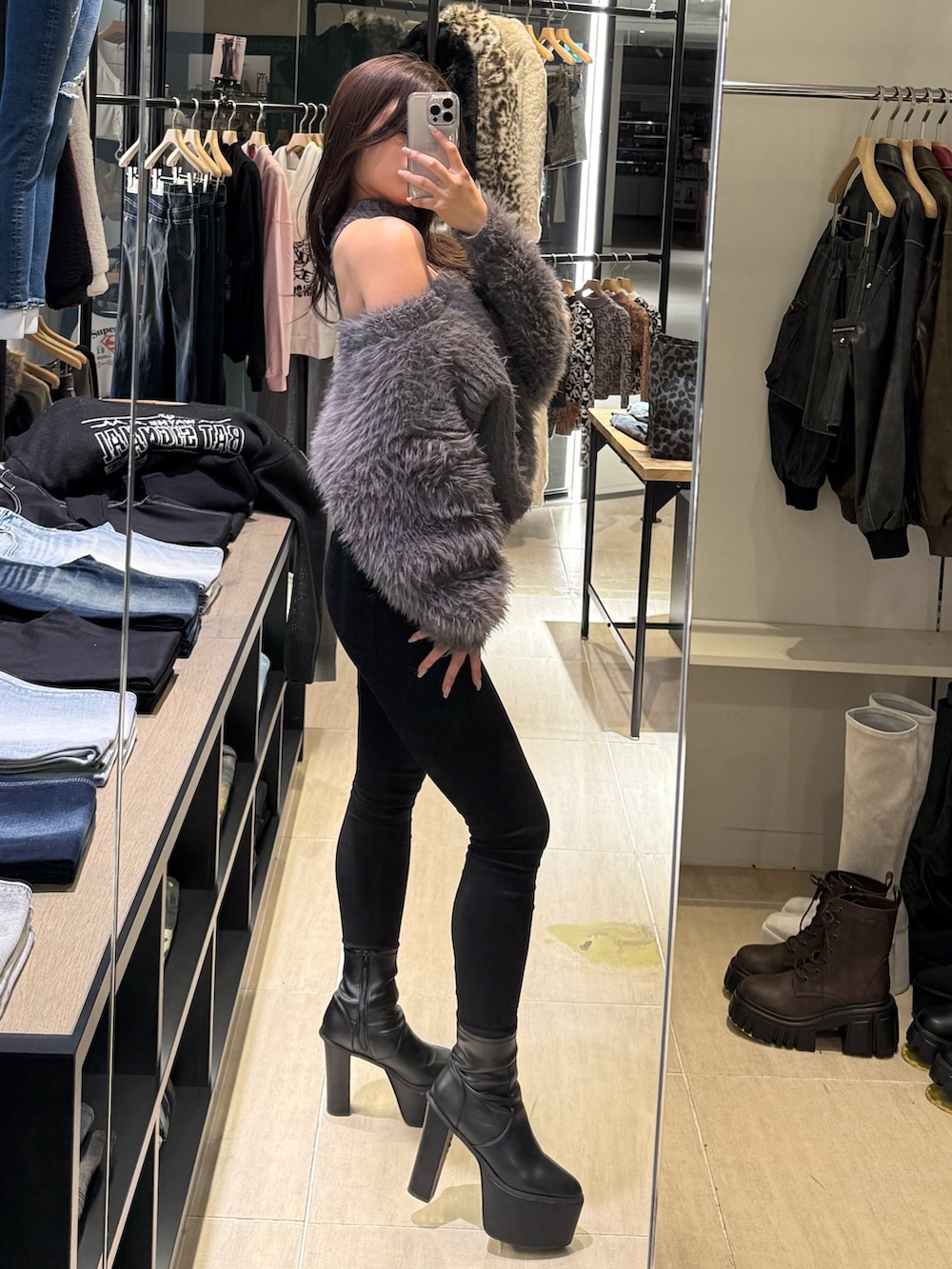 グレー系のニット/セーター、ブラック系のデニムパンツ、ブラック系のブーツを着用したレディースの秋コーディネートの2枚目の写真