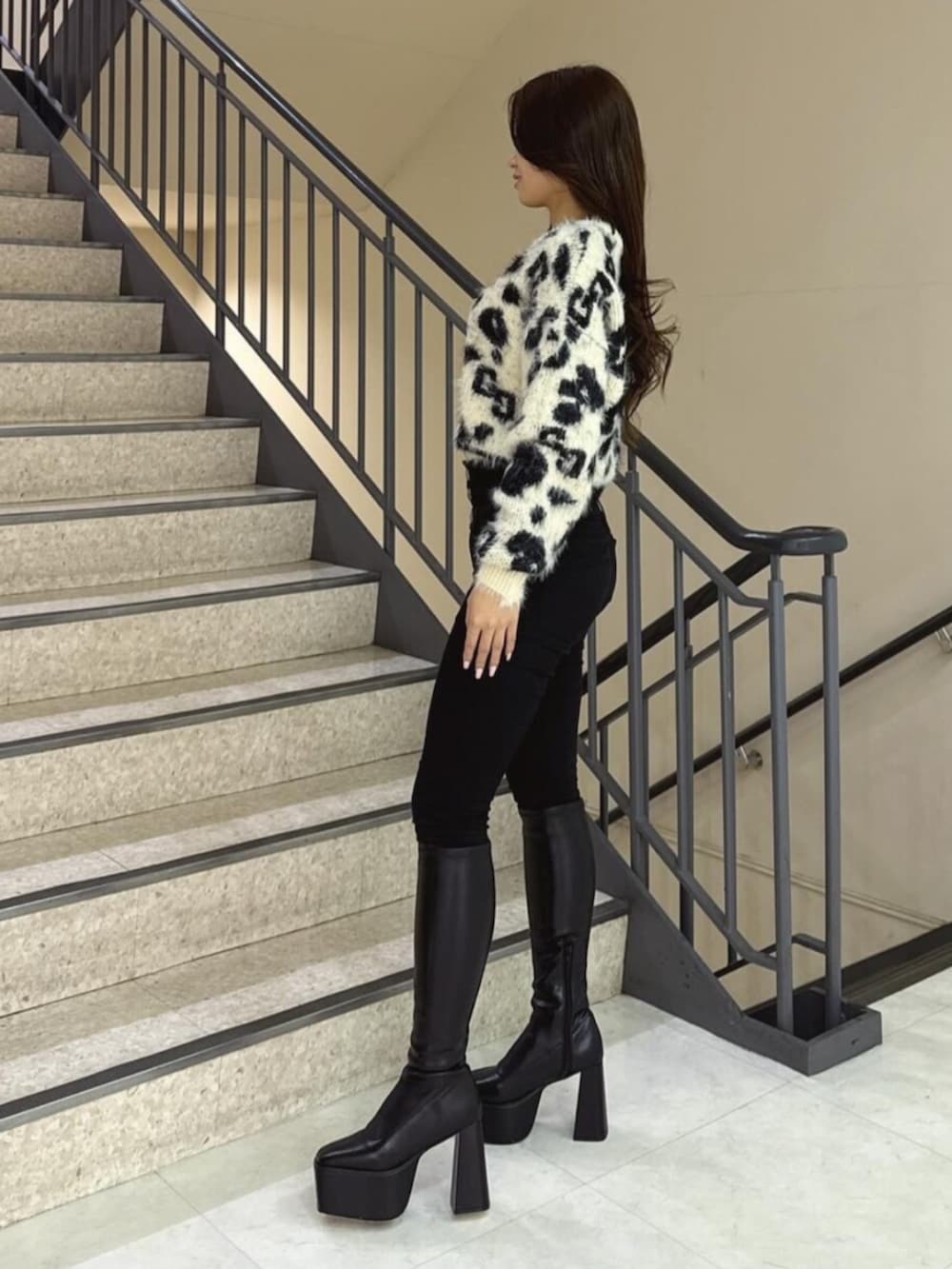 ブラック系のデニムパンツ、ホワイト系のニット/セーター、ブラック系のブーツを着用したレディースの冬コーディネートの2枚目の写真