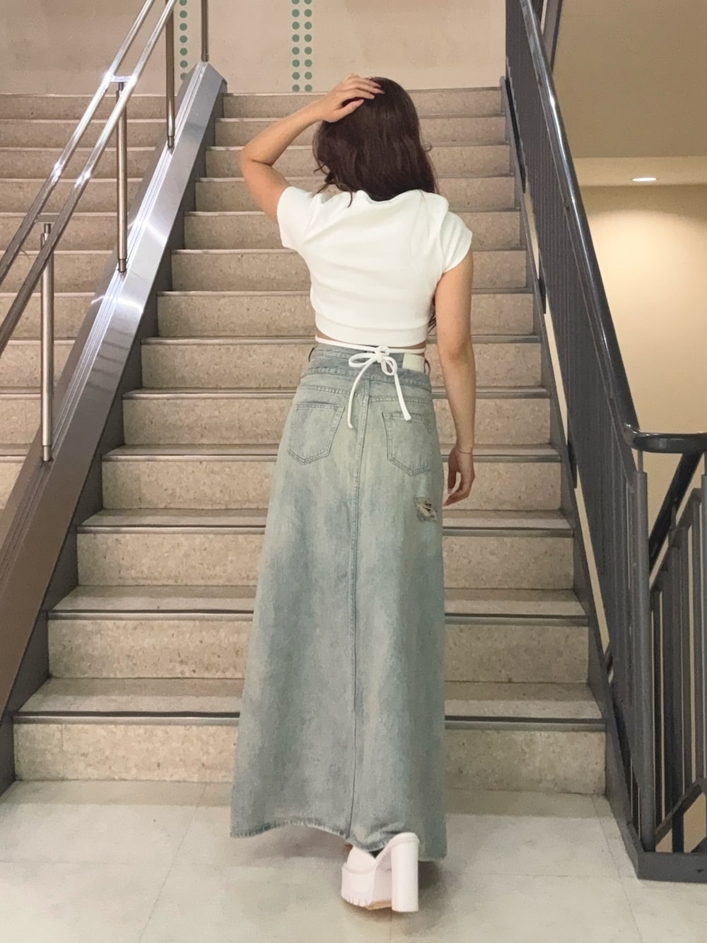 ブルー系のデニムスカート、ホワイト系のTシャツ/カットソー、ホワイト系のサンダルを着用したレディースの夏コーディネートの3枚目の写真