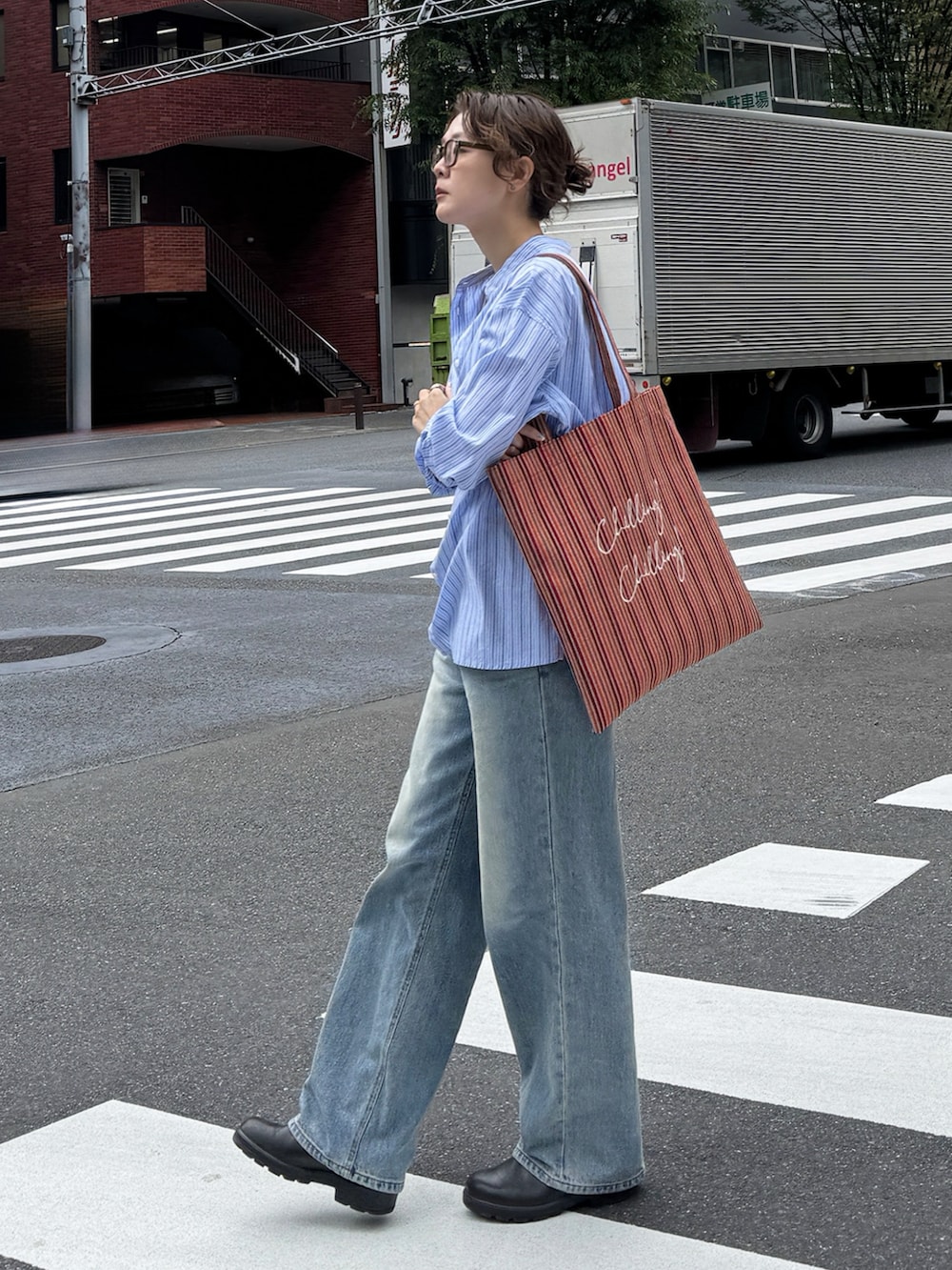 ブルー系のシャツ/ブラウス、オレンジ系のトートバッグ、ブラウン系のブーツを着用したレディースの夏コーディネートの4枚目の写真