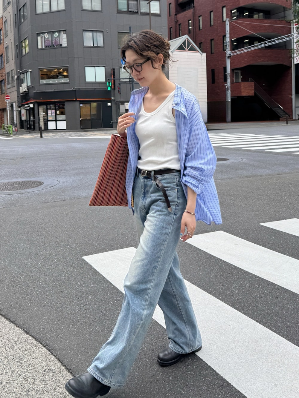 ブルー系のシャツ/ブラウス、オレンジ系のトートバッグ、ブラウン系のブーツを着用したレディースの夏コーディネートの3枚目の写真