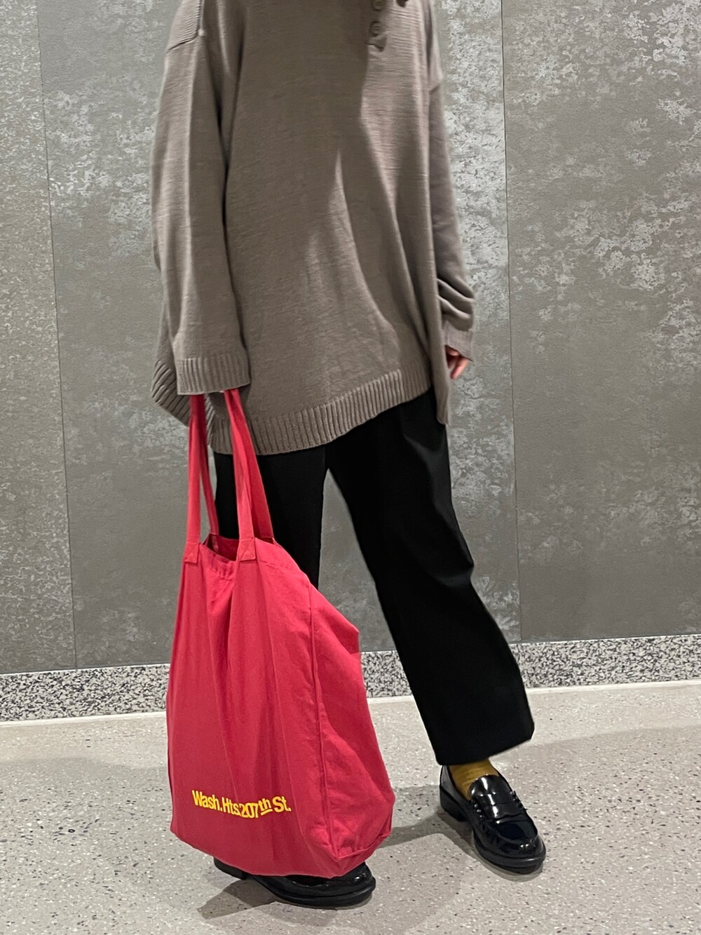 グレー系のニット/セーター、ブラック系のスラックス、レッド系のトートバッグを着用したメンズの秋コーディネートの2枚目の写真