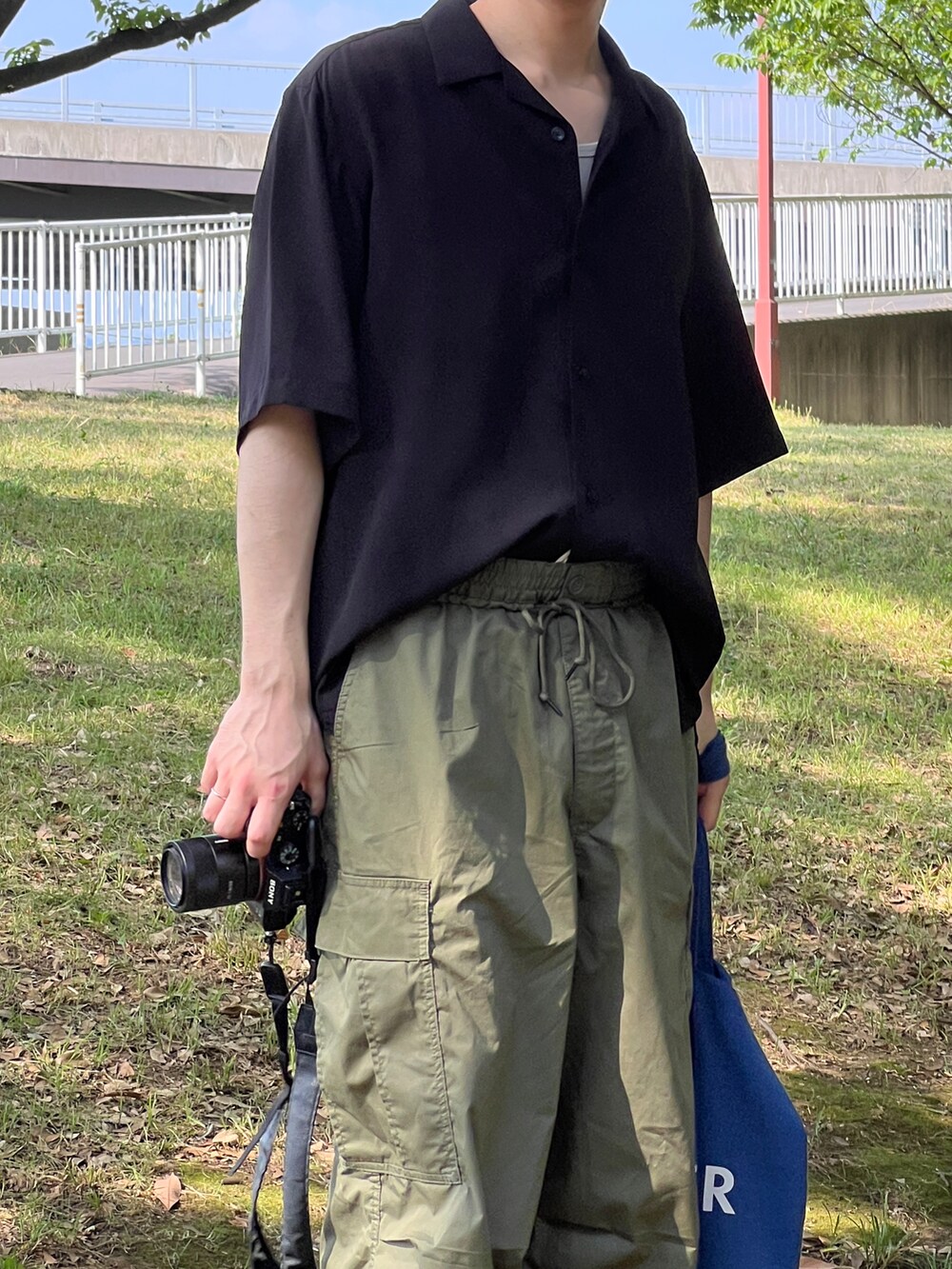 ブラック系のシャツ/ブラウス、グリーン系のカーゴパンツ、ブラック系のモカシン/デッキシューズを着用したメンズの夏コーディネートの2枚目の写真