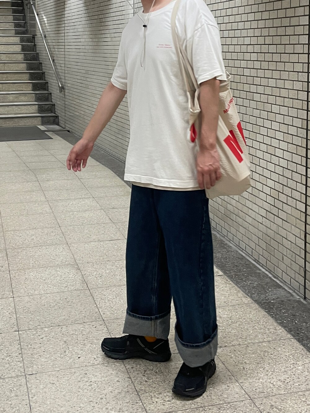 ブラック系のスニーカー、ホワイト系のTシャツ/カットソー、ブルー系のデニムパンツを着用したメンズの秋コーディネートの2枚目の写真