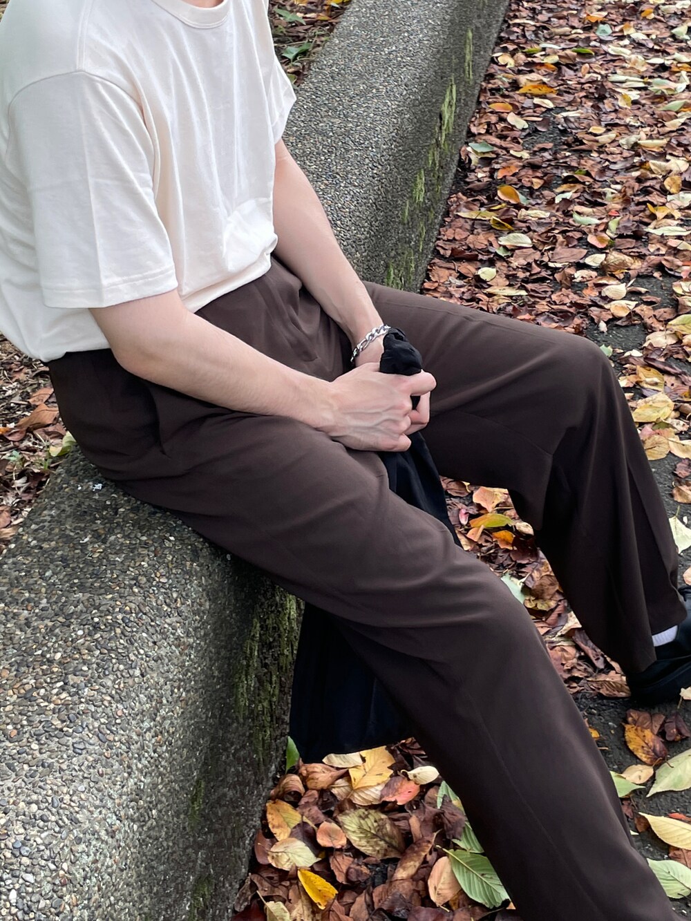 ベージュ系のTシャツ/カットソー、ブラウン系のスラックス、ブラック系のシューズを着用したメンズの夏コーディネートの3枚目の写真