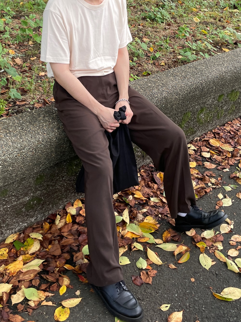 ベージュ系のTシャツ/カットソー、ブラウン系のスラックス、ブラック系のシューズを着用したメンズの夏コーディネートの2枚目の写真