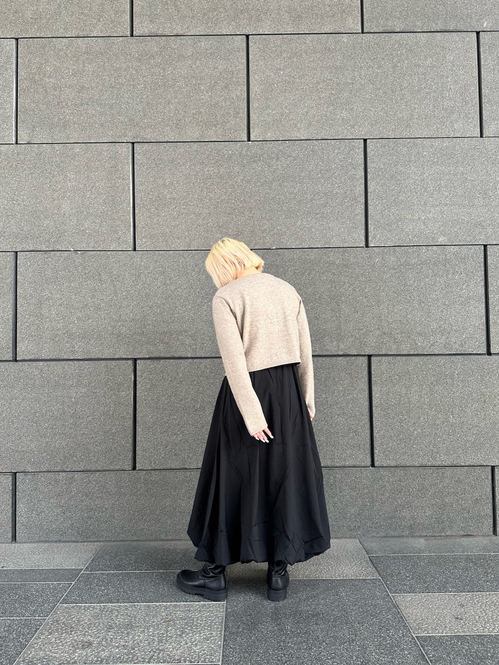 ベージュ系のカーディガン/ボレロ、ブラック系のスカート、ブラック系のブーツを着用したレディースの冬コーディネートの2枚目の写真