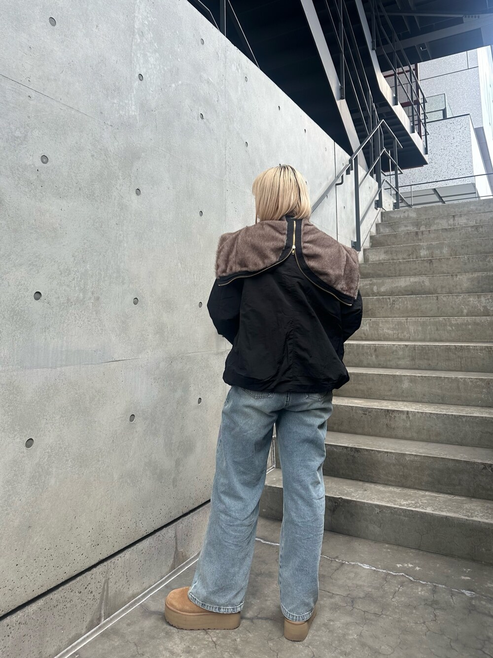 レッド系のニット/セーター、ブルー系のデニムパンツ、ブラック系のブルゾンを着用したレディースの秋コーディネートの2枚目の写真