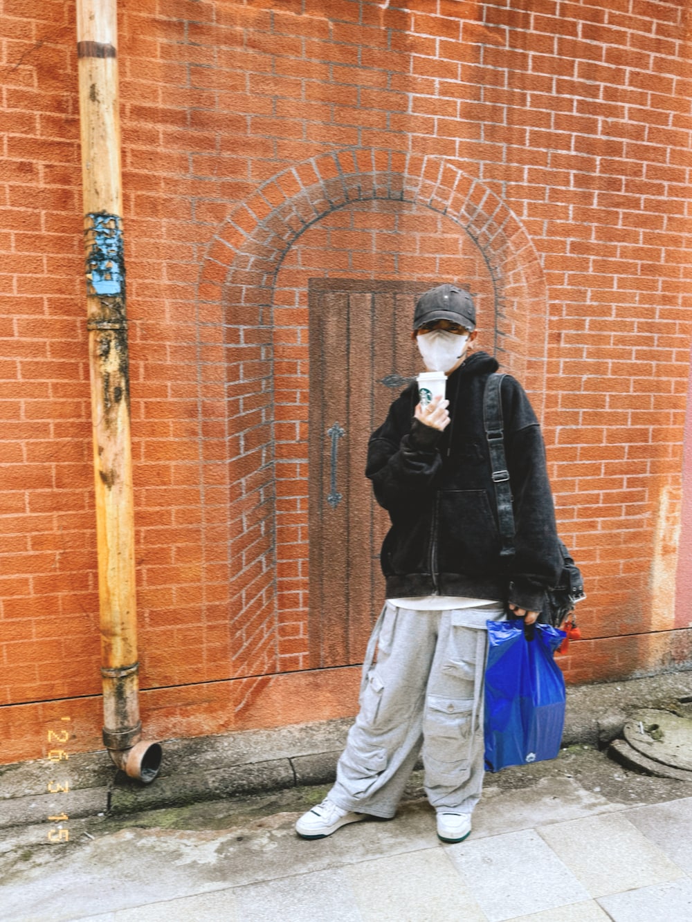 ブラック系のパーカー、グレー系のカーゴパンツ、ブラック系のショルダーバッグを着用したメンズの春コーディネートの2枚目の写真