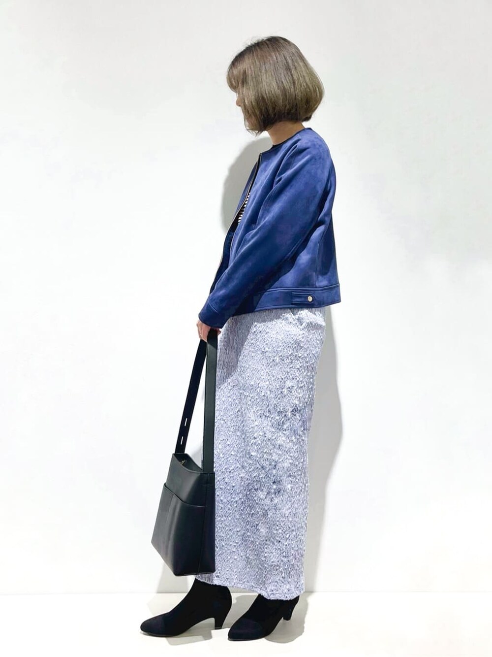 ブルー系のブルゾン、ブラック系のニット/セーター、ブルー系のスカートを着用したレディースの春コーディネートの2枚目の写真