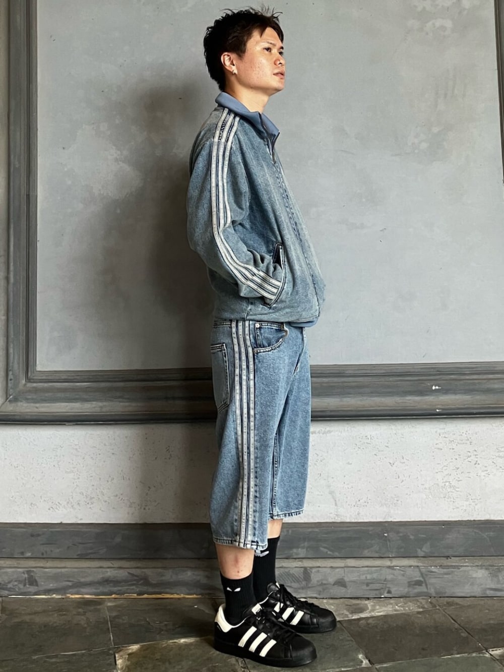 ブルー系のデニムパンツ、ブルー系のデニムジャケット、ブラック系のスニーカーを着用したメンズの秋コーディネートの2枚目の写真