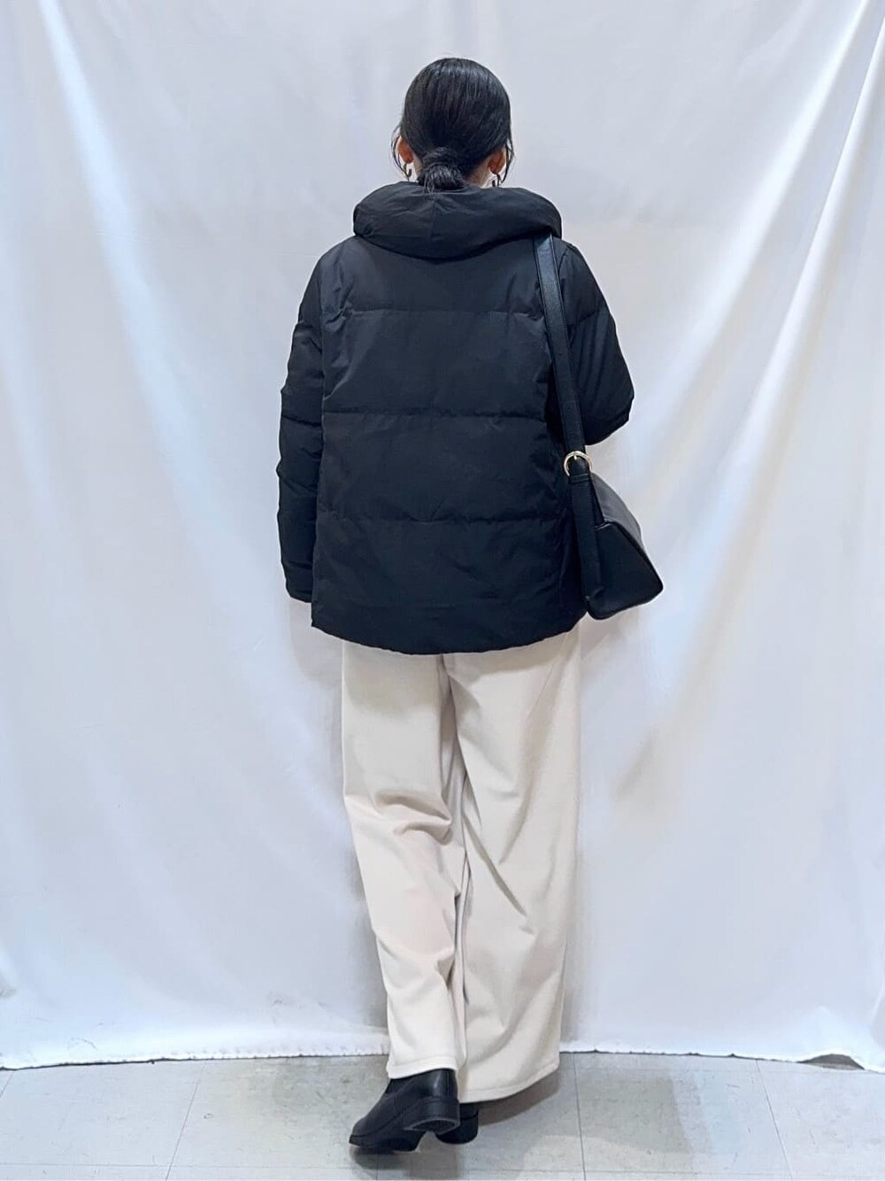 ブラック系のダウンジャケット/コート、ピンク系のニット/セーター、ホワイト系のその他パンツを着用したレディースの冬コーディネートの3枚目の写真