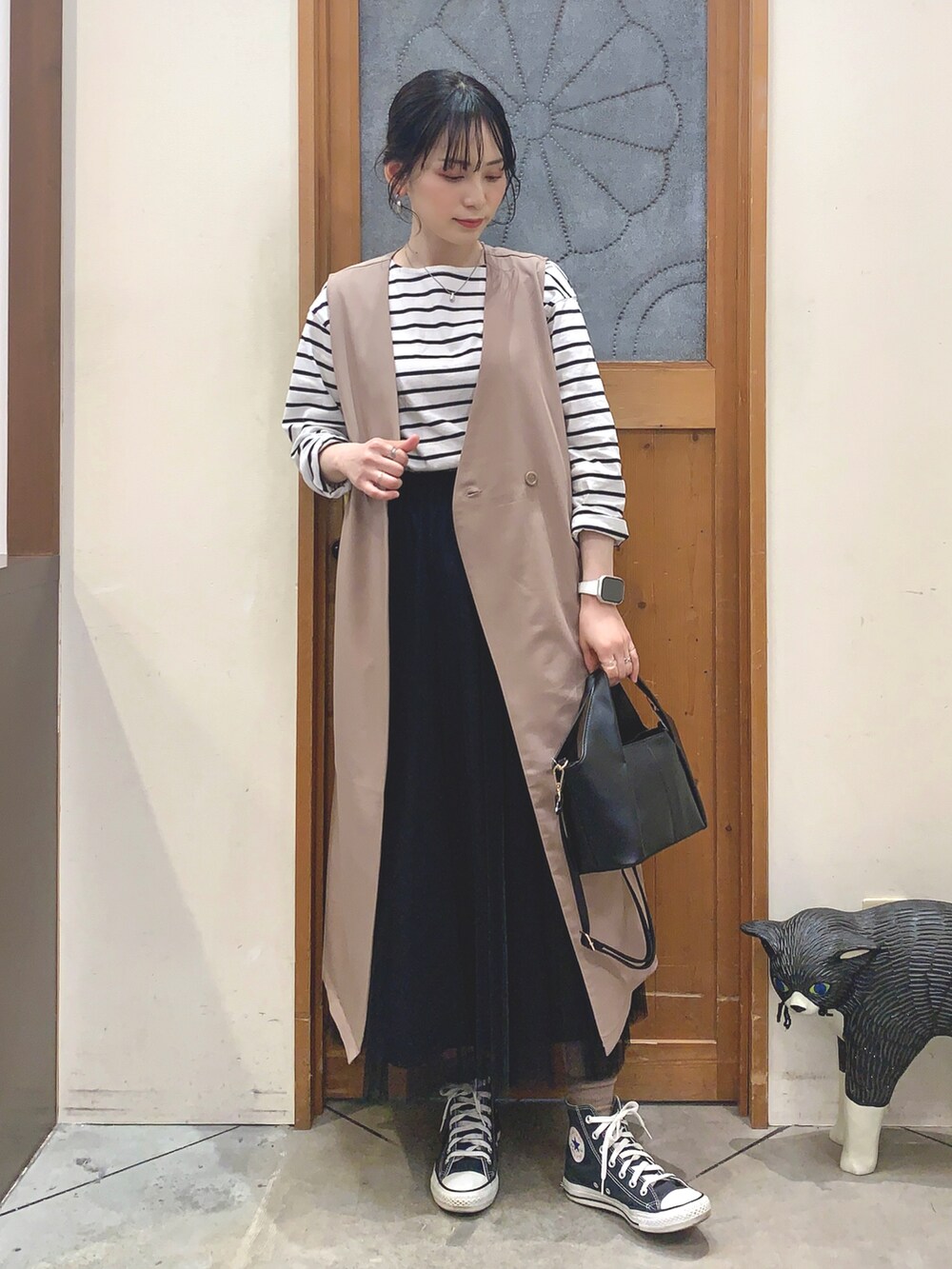 ブラック系のTシャツ/カットソー、ベージュ系のベスト、ブラック系のスカートを着用したレディースの春コーディネートの2枚目の写真