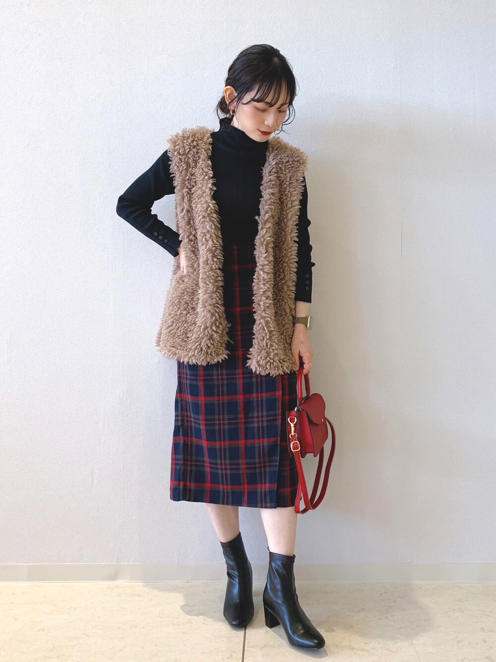 ブラック系のニット/セーター、ブラウン系のベスト、ブルー系のスカートを着用したレディースの秋コーディネートの2枚目の写真