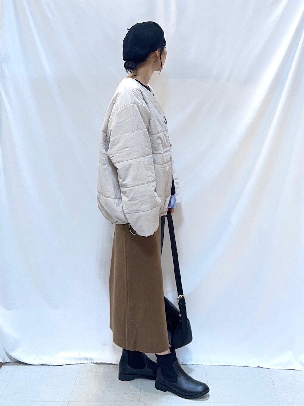 ベージュ系のブルゾン、ブルー系のニット/セーター、ブラウン系のスカートを着用したレディースの冬コーディネートの2枚目の写真