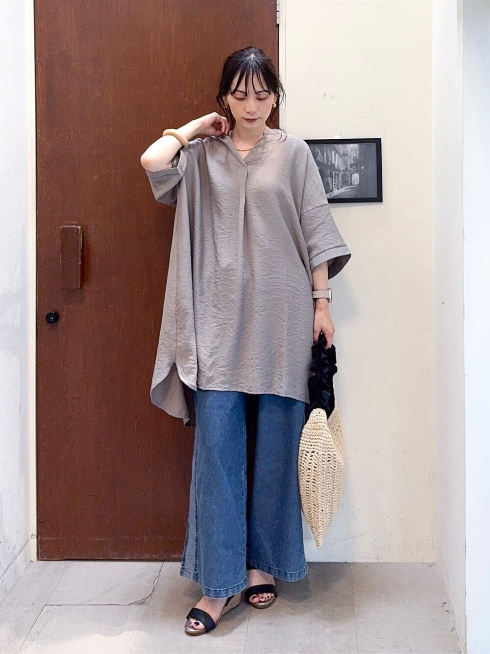 ブラウン系のチュニック、ブルー系のデニムパンツ、ブラック系のサンダルを着用したレディースの夏コーディネートの3枚目の写真