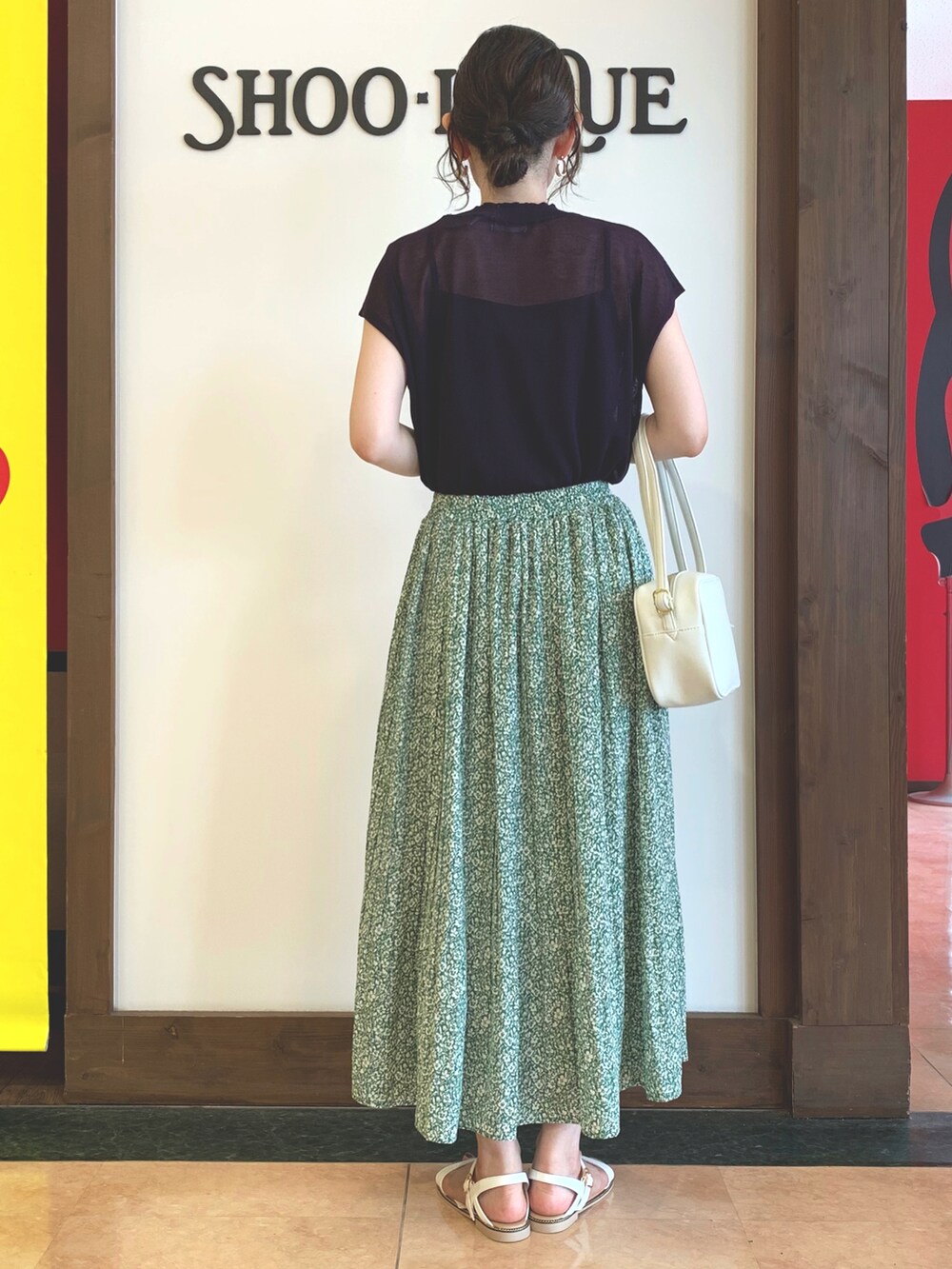 ブルー系のニット/セーター、グリーン系のスカート、ホワイト系のショルダーバッグを着用したレディースの夏コーディネートの3枚目の写真