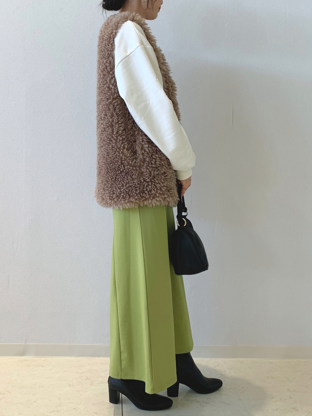 ベージュ系のスウェット、ブラウン系のベスト、グリーン系のスカートを着用したレディースの秋コーディネートの2枚目の写真