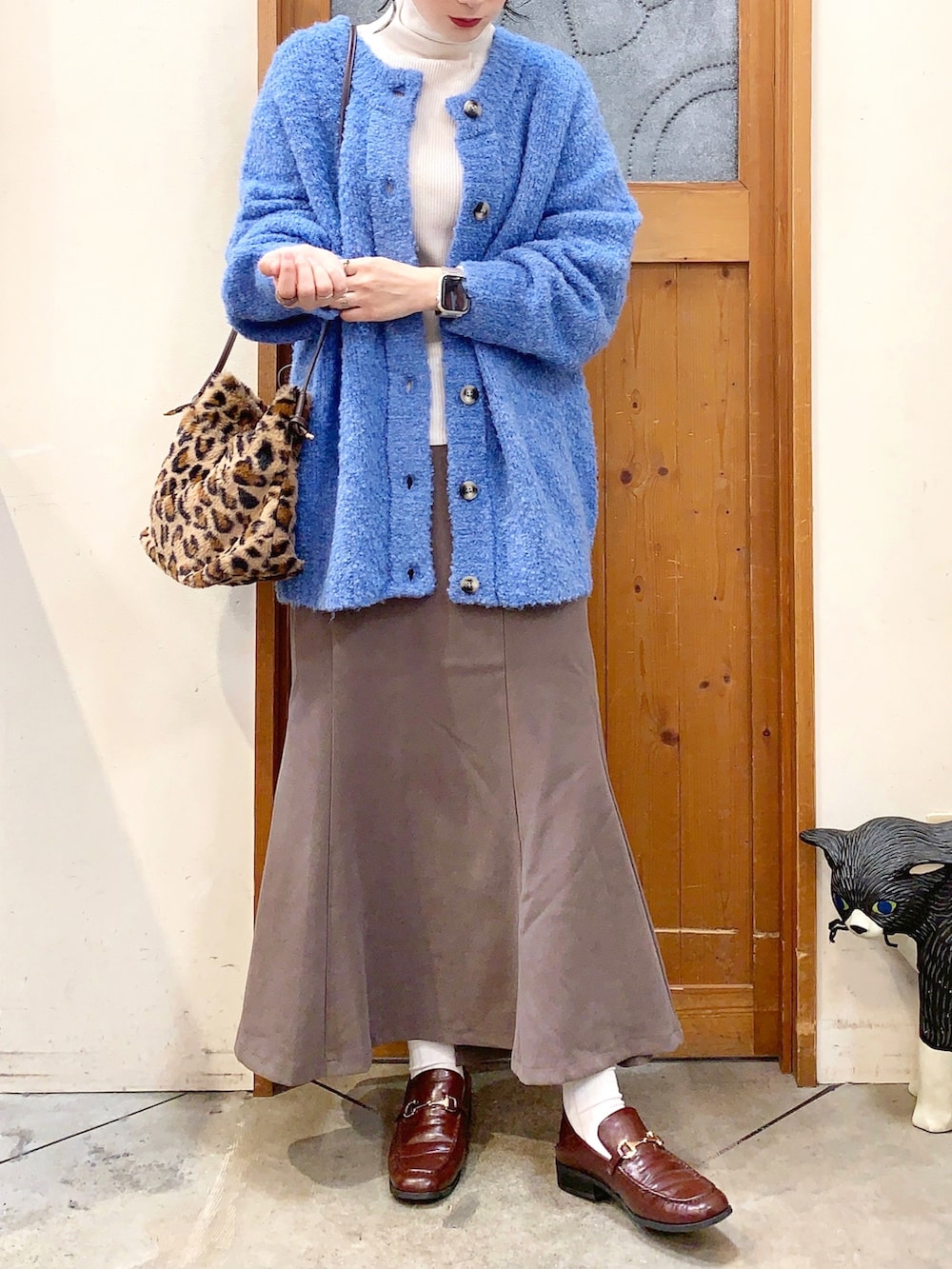ホワイト系のニット/セーター、ブルー系のカーディガン/ボレロ、ブラウン系のスカートを着用したレディースの秋コーディネートの3枚目の写真