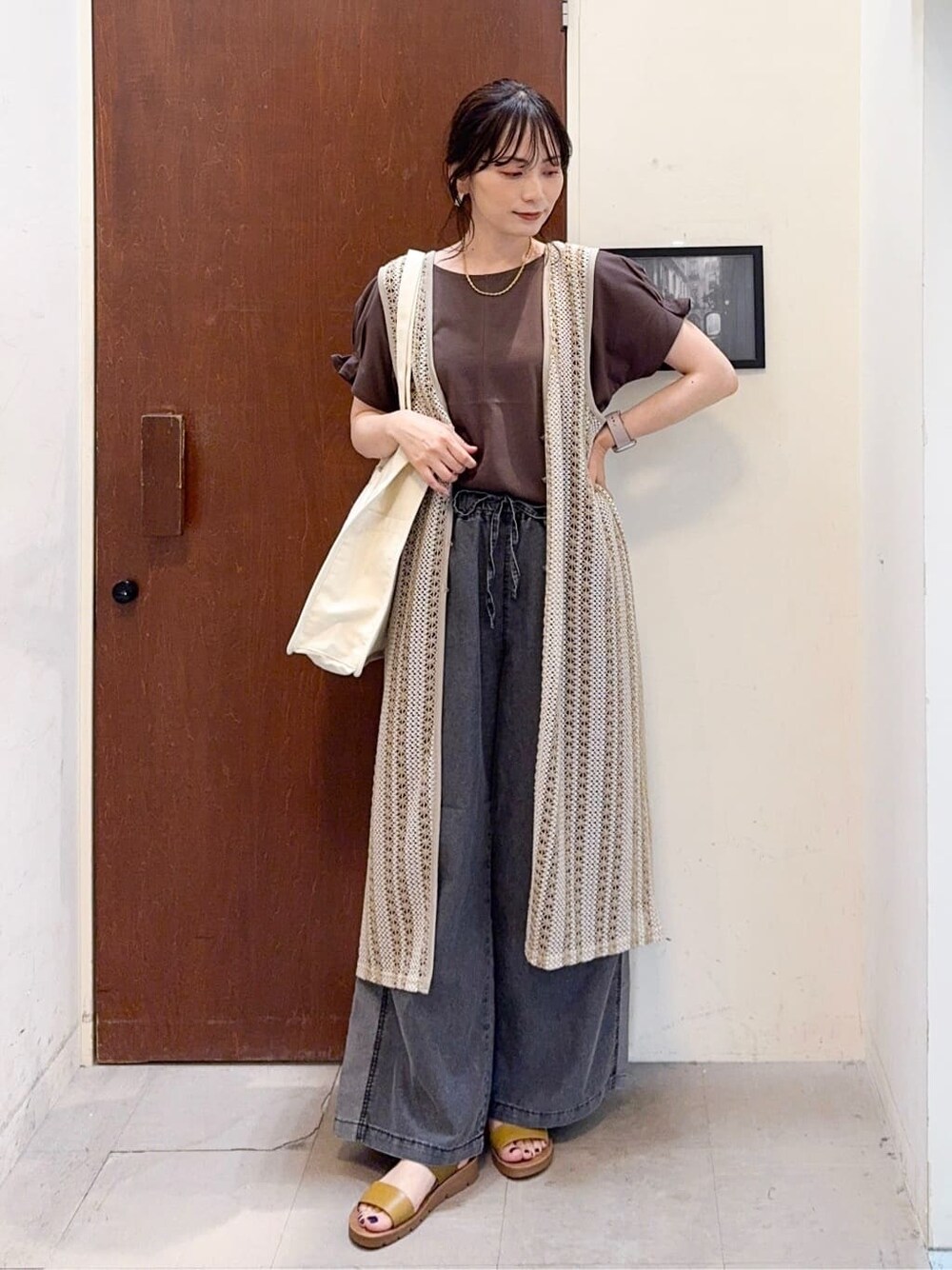 ベージュ系のベスト、ブラウン系のTシャツ/カットソー、ブラック系のデニムパンツを着用したレディースの夏コーディネートの2枚目の写真