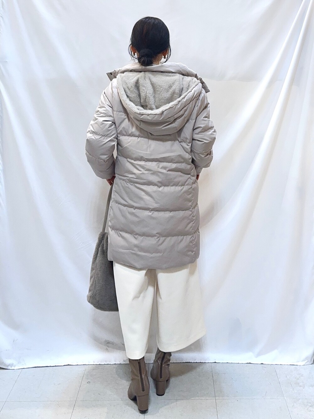 ベージュ系のダウンジャケット/コート、イエロー系のニット/セーター、ホワイト系のその他パンツを着用したレディースの冬コーディネートの4枚目の写真