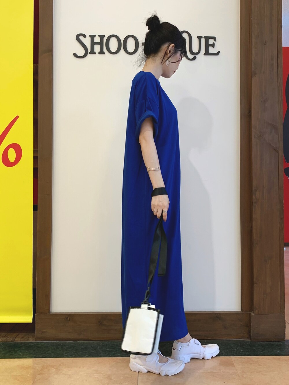 ブルー系のワンピース、ホワイト系のショルダーバッグ、ホワイト系のスニーカーを着用したレディースの夏コーディネートの2枚目の写真