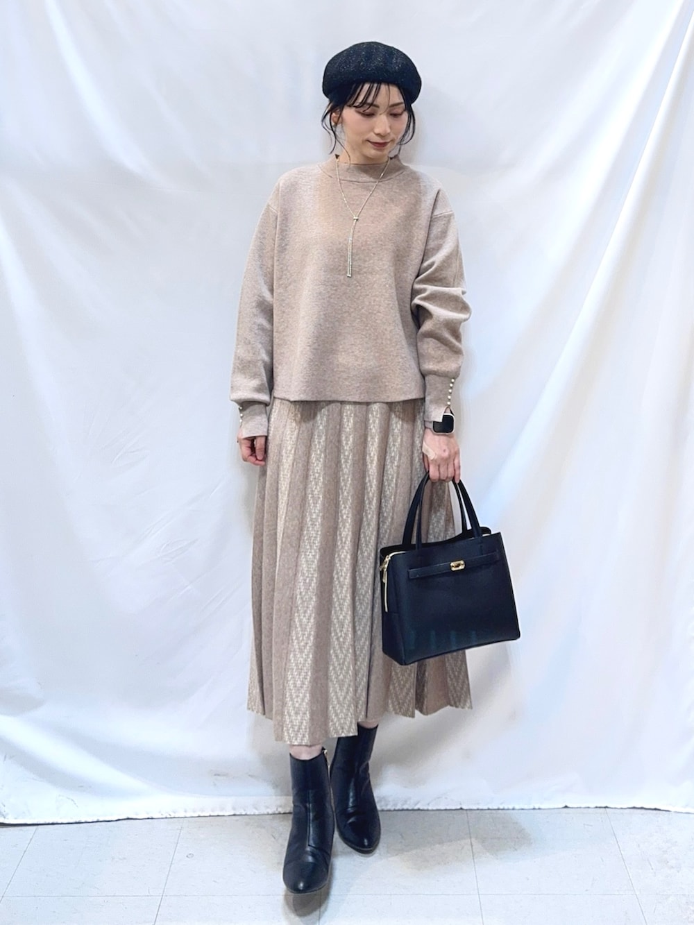 ベージュ系のニット/セーター、ベージュ系のスカート、ブラック系のトートバッグを着用したレディースの冬コーディネートの3枚目の写真