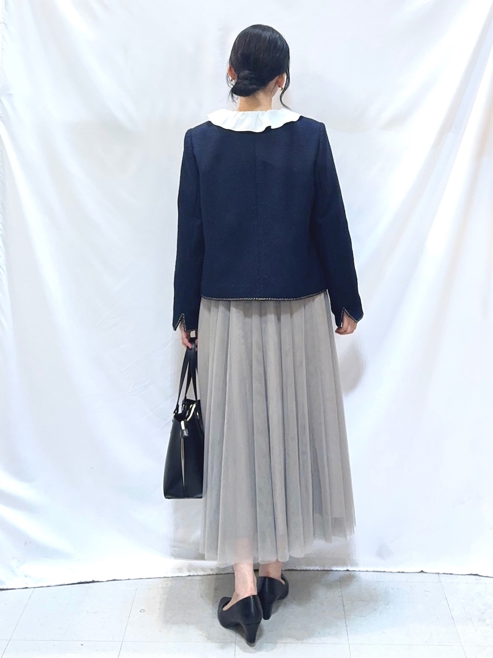 ブルー系のノーカラージャケット、ホワイト系のシャツ/ブラウス、ベージュ系のスカートを着用したレディースの冬コーディネートの4枚目の写真