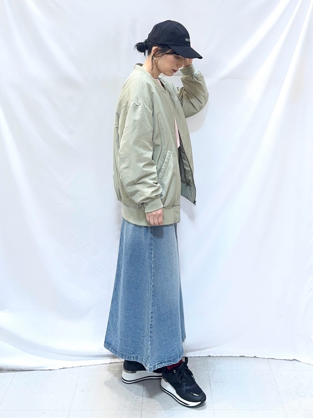 グリーン系のブルゾン、ピンク系のニット/セーター、ブルー系のデニムスカートを着用したレディースの冬コーディネートの3枚目の写真