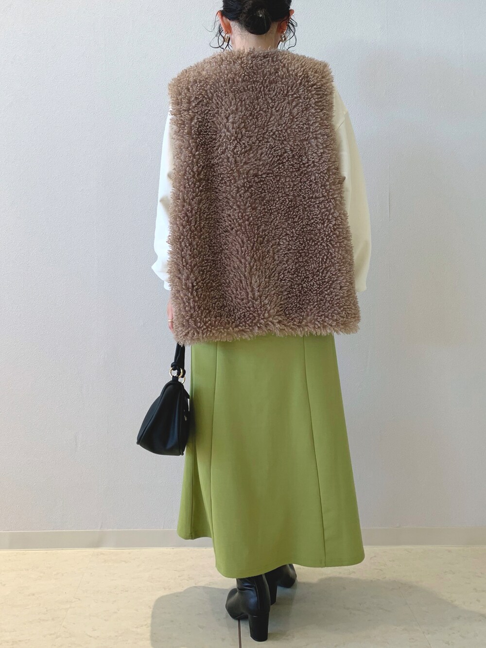 ベージュ系のスウェット、ブラウン系のベスト、グリーン系のスカートを着用したレディースの秋コーディネートの3枚目の写真