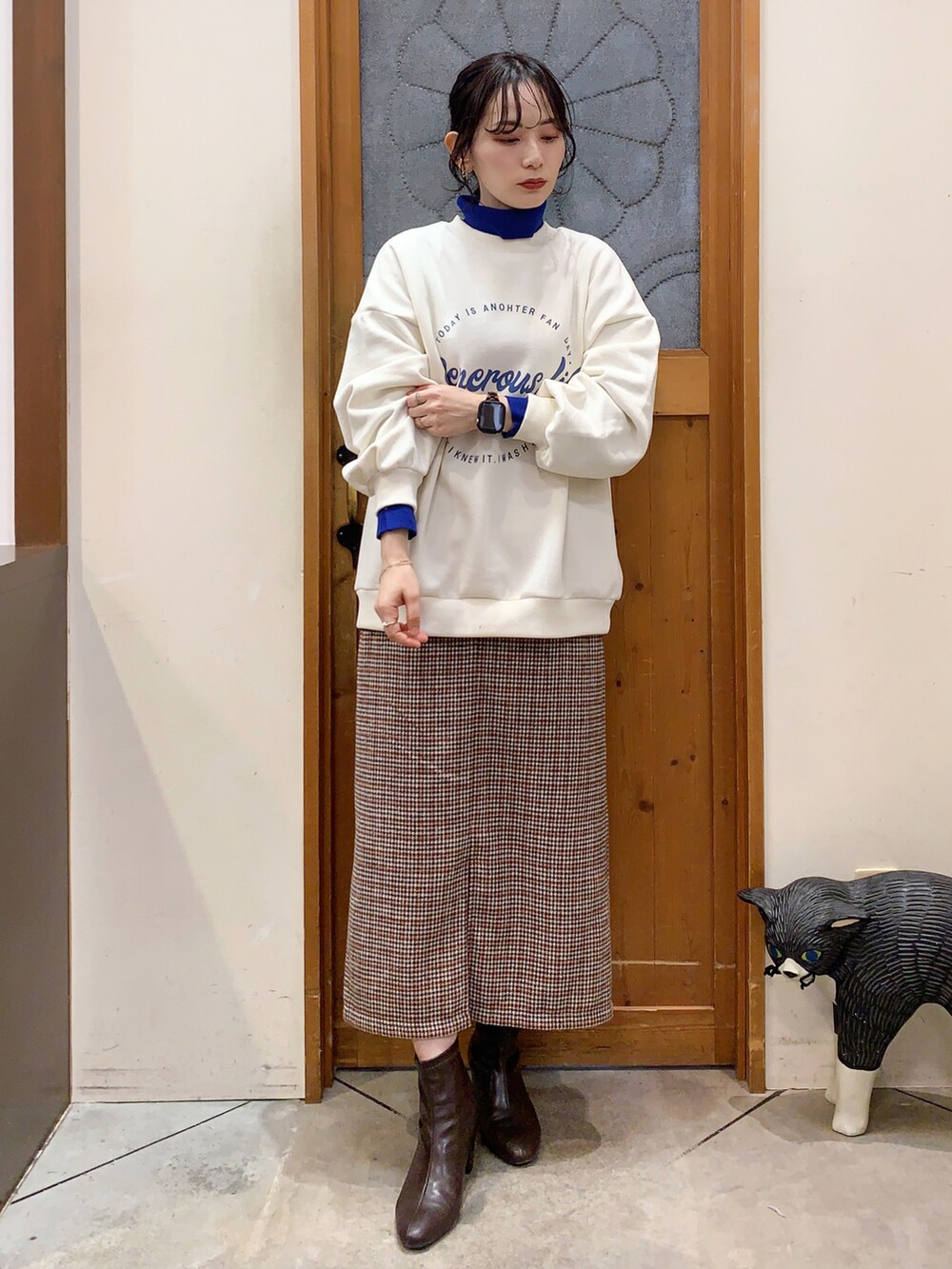 ホワイト系のスウェット、ブルー系のニット/セーター、ベージュ系のスカートを着用したレディースの冬コーディネートの2枚目の写真
