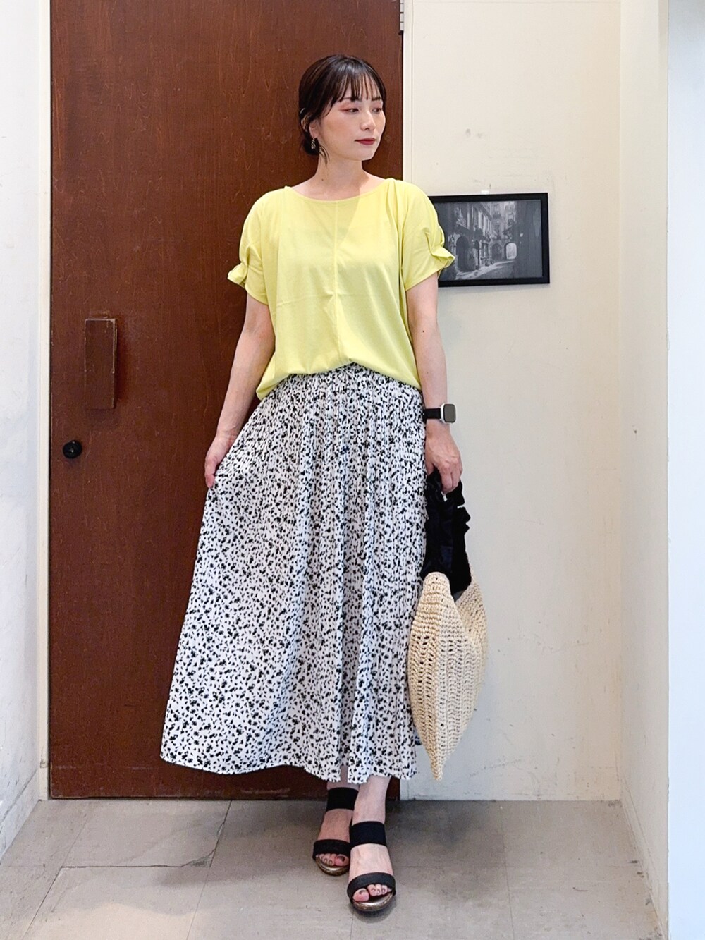 イエロー系のTシャツ/カットソー、ホワイト系のスカート、ブラック系のトートバッグを着用したレディースの夏コーディネートの2枚目の写真