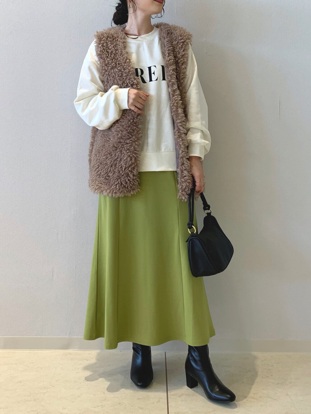 ベージュ系のスウェット、ブラウン系のベスト、グリーン系のスカートを着用したレディースの秋コーディネートの4枚目の写真