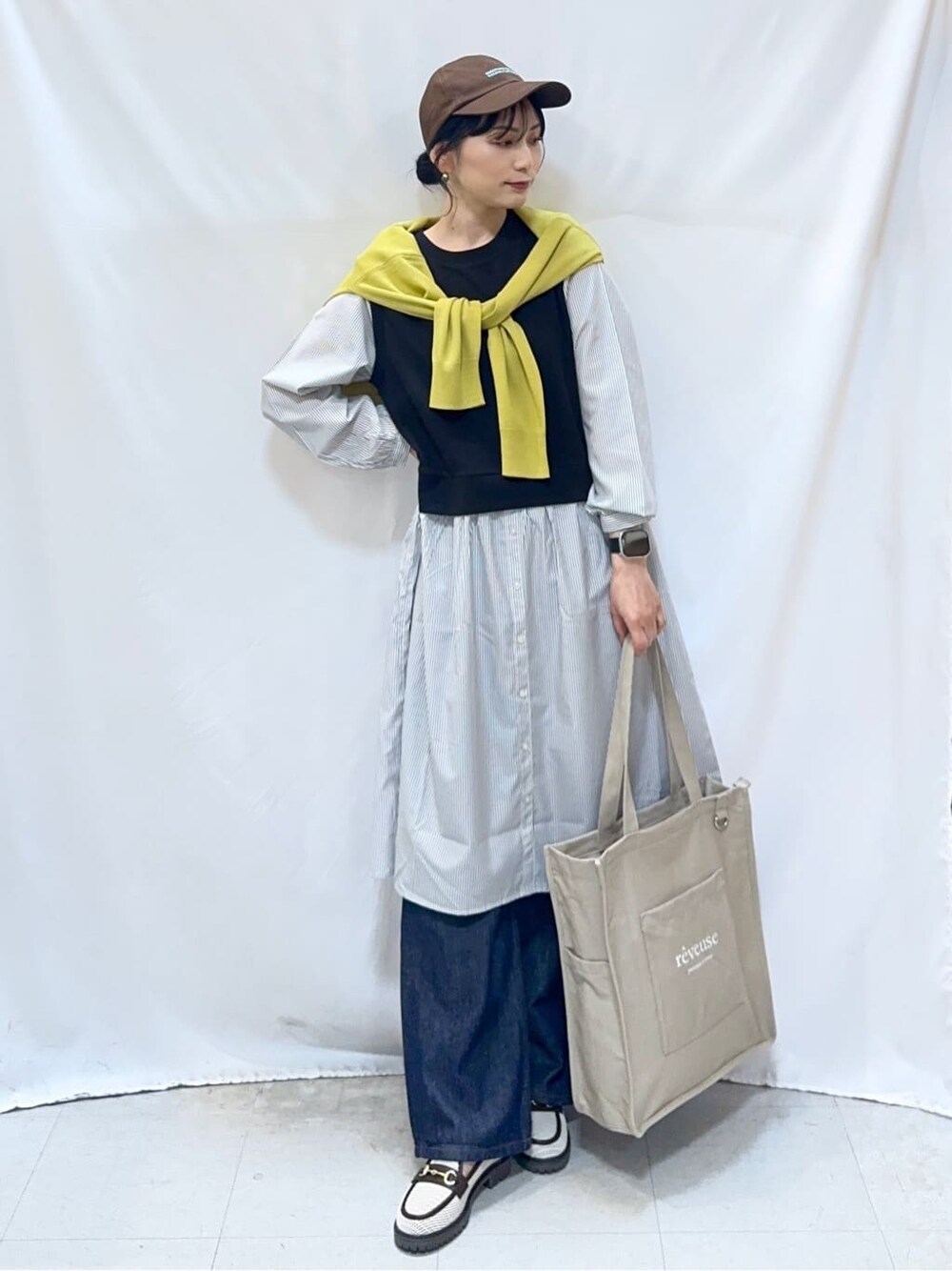 イエロー系のカーディガン/ボレロ、ブラック系のワンピース、ブルー系のデニムパンツを着用したレディースの春コーディネートの2枚目の写真