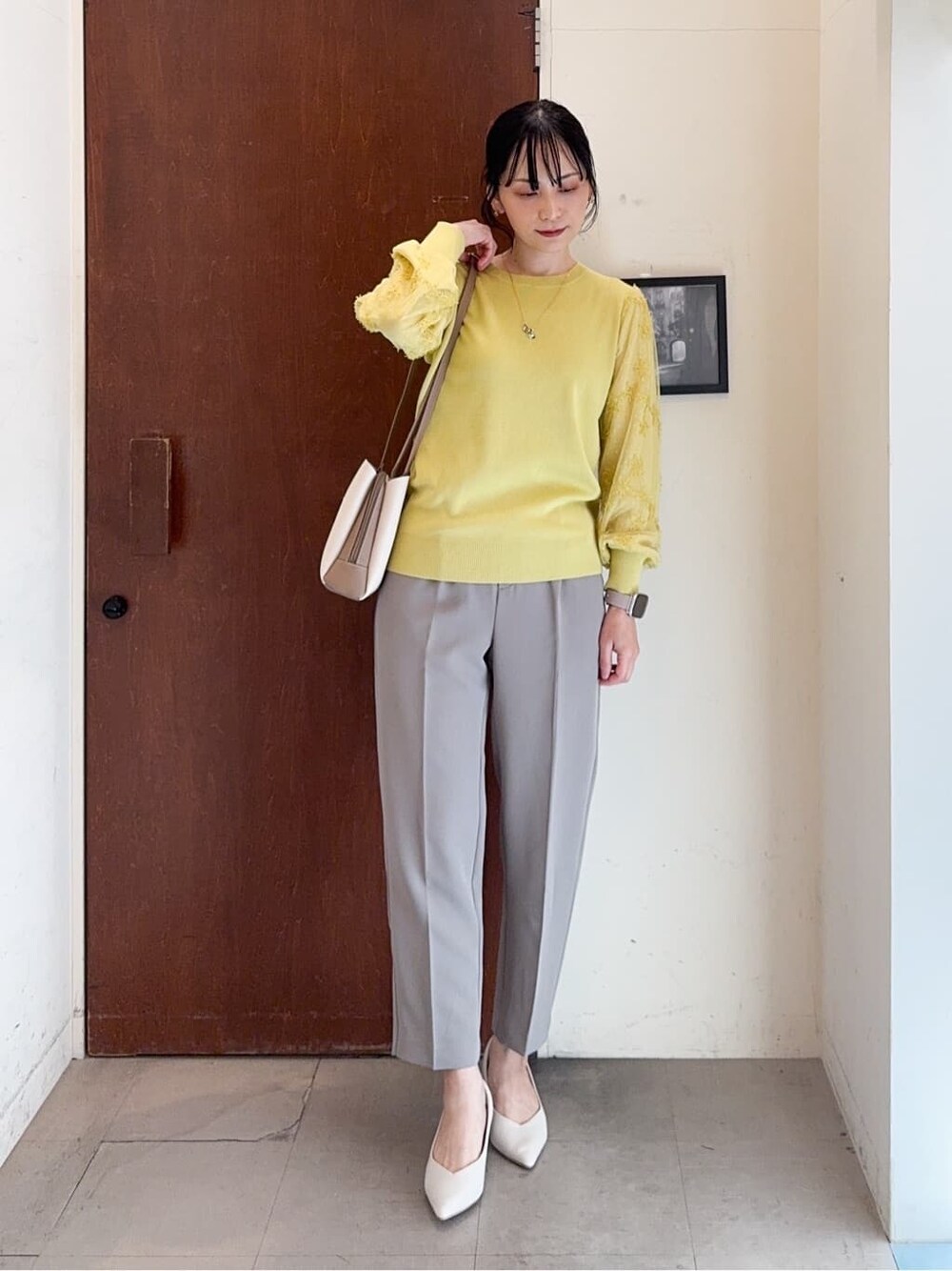 イエロー系のニット/セーター、ブラウン系のその他パンツ、ホワイト系のパンプスを着用したレディースの春コーディネートの2枚目の写真