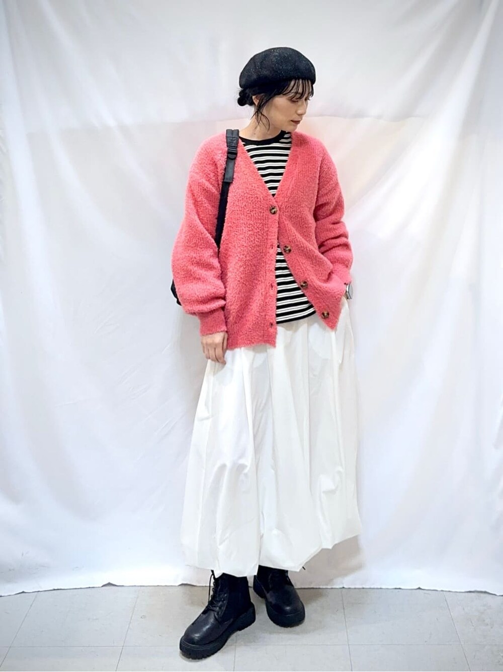 ピンク系のカーディガン/ボレロ、ブラック系のTシャツ/カットソー、ホワイト系のスカートを着用したレディースの秋コーディネートの2枚目の写真