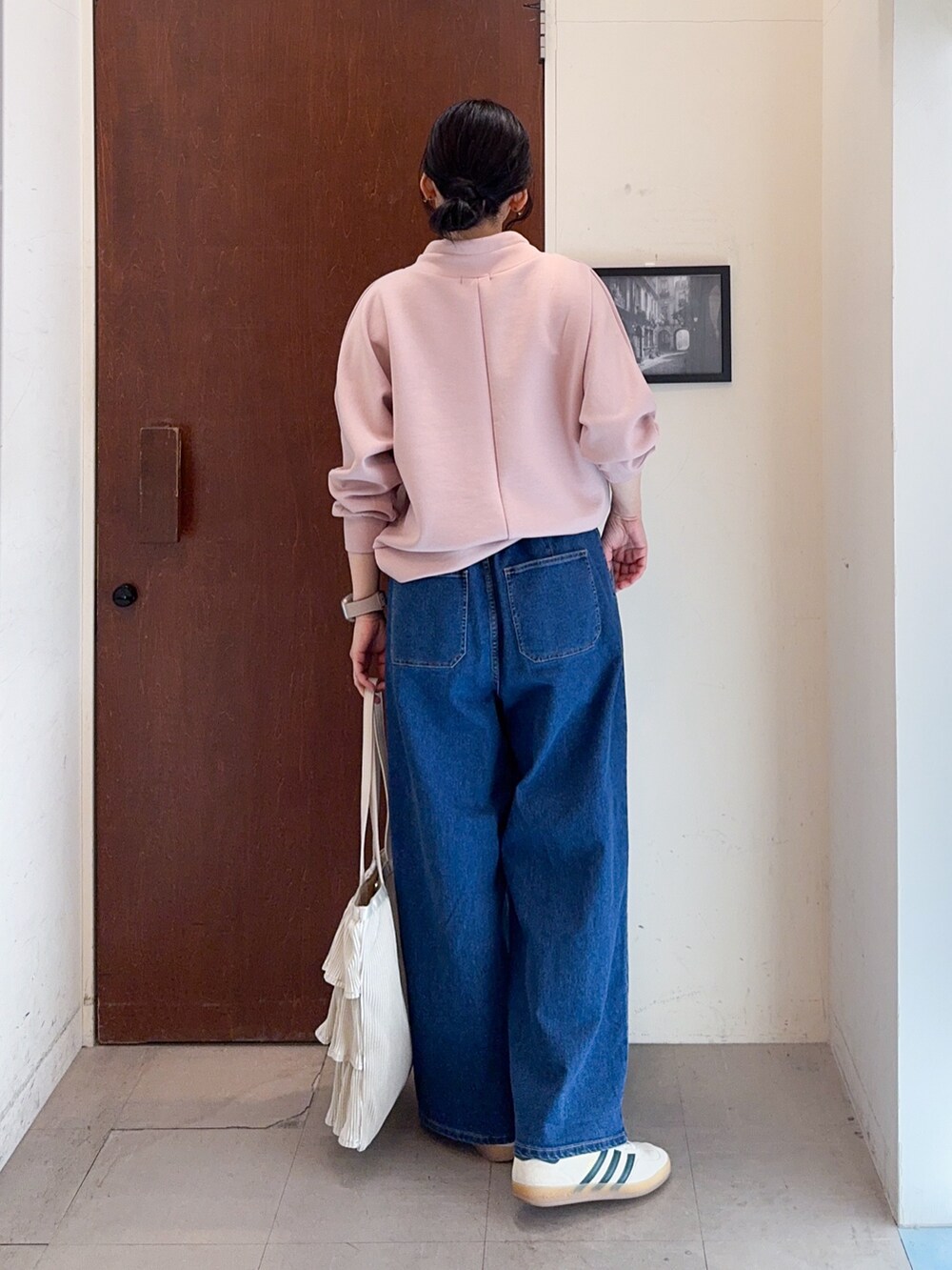ピンク系のTシャツ/カットソー、ブルー系のデニムパンツ、ベージュ系のトートバッグを着用したレディースの冬コーディネートの3枚目の写真