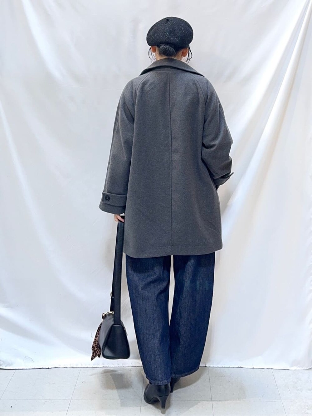 グレー系のチェスターコート、レッド系のニット/セーター、ブルー系のデニムパンツを着用したレディースの冬コーディネートの4枚目の写真