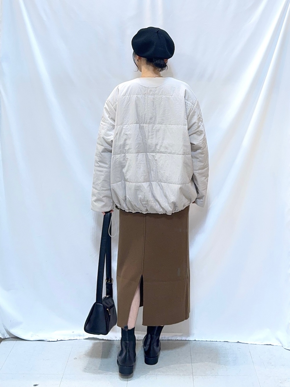 ベージュ系のブルゾン、ブルー系のニット/セーター、ブラウン系のスカートを着用したレディースの冬コーディネートの3枚目の写真