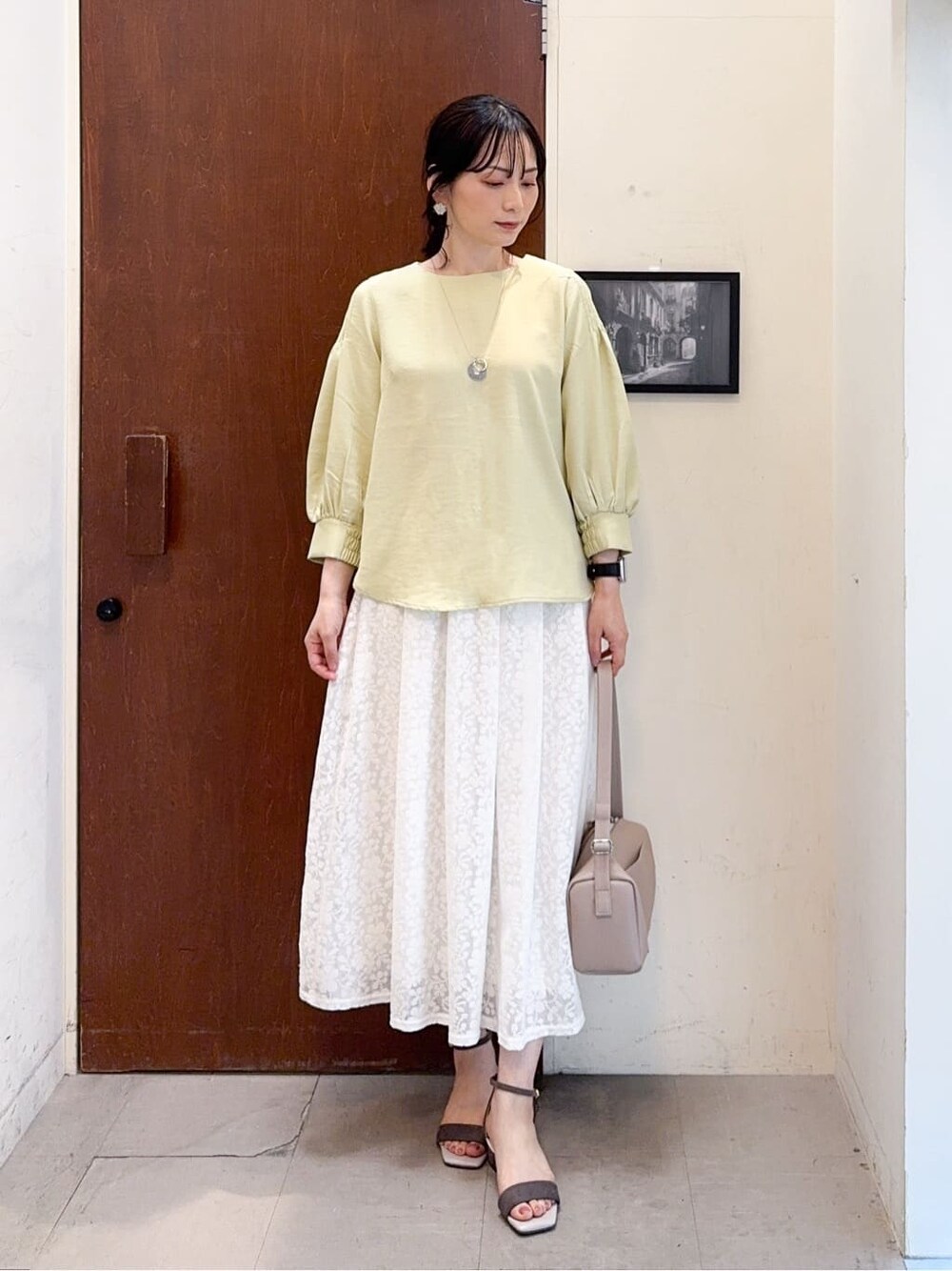 イエロー系のシャツ/ブラウス、ホワイト系のスカート、ベージュ系のサンダルを着用したレディースの春コーディネートの2枚目の写真